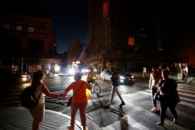 Pedestrians cross the street during the blackout ( Michael Owens/AP/Shutterstock)